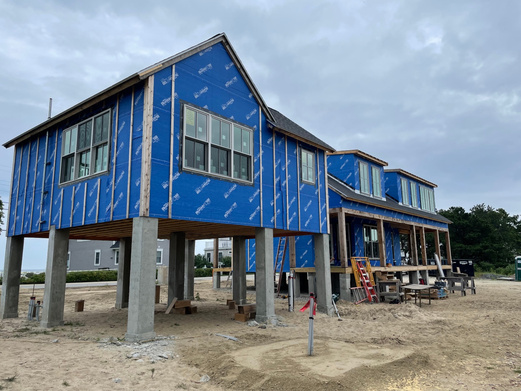 Side view of the elevated home showing concrete pier foundation and Blueskin wrap