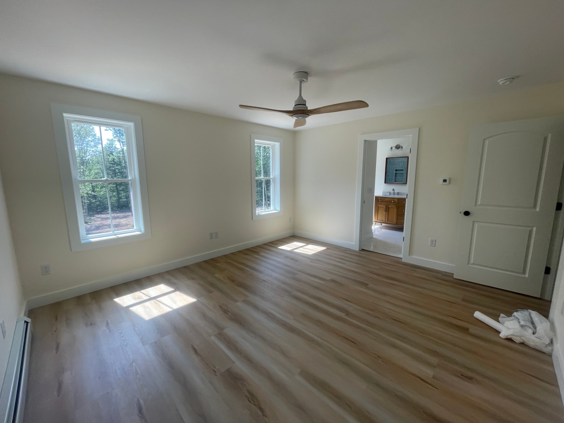 Primary bedroom with ceiling fan, natural light, and en-suite bath entry