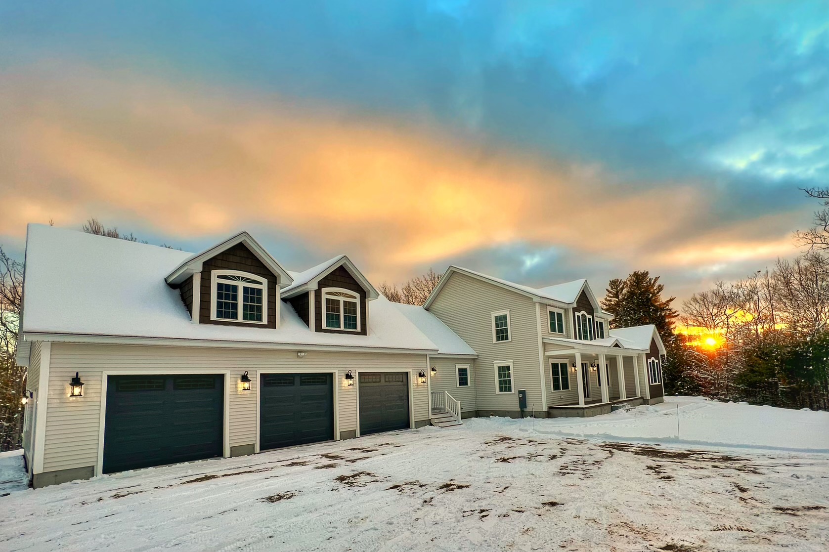 Finished exterior at sunset with three-car garage and snow-covered roof