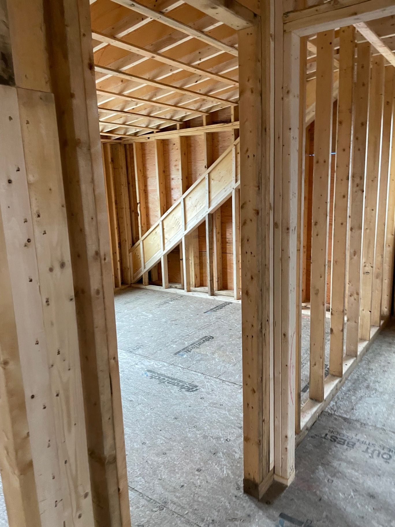 Interior framing looking through a doorway toward the stick-framed staircase