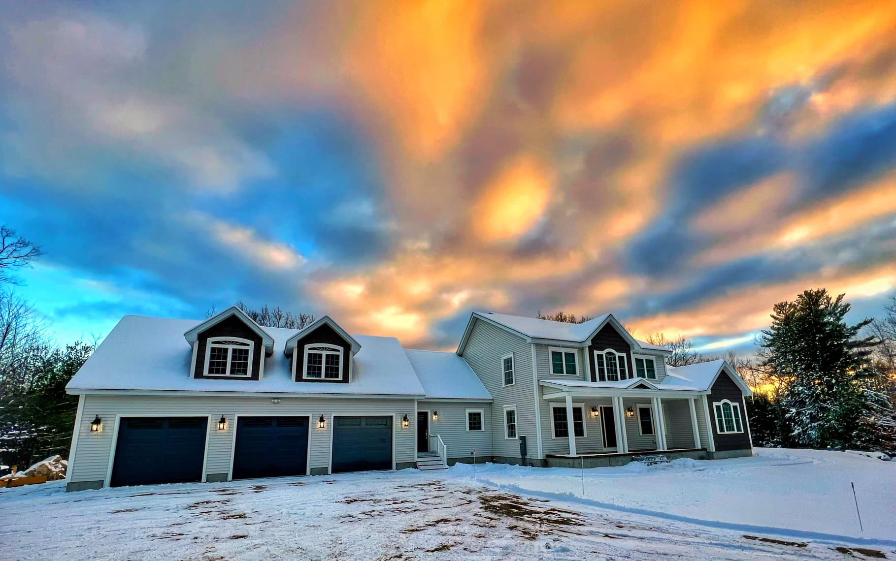 Custom-built Maine home at sunset with snow-covered roof