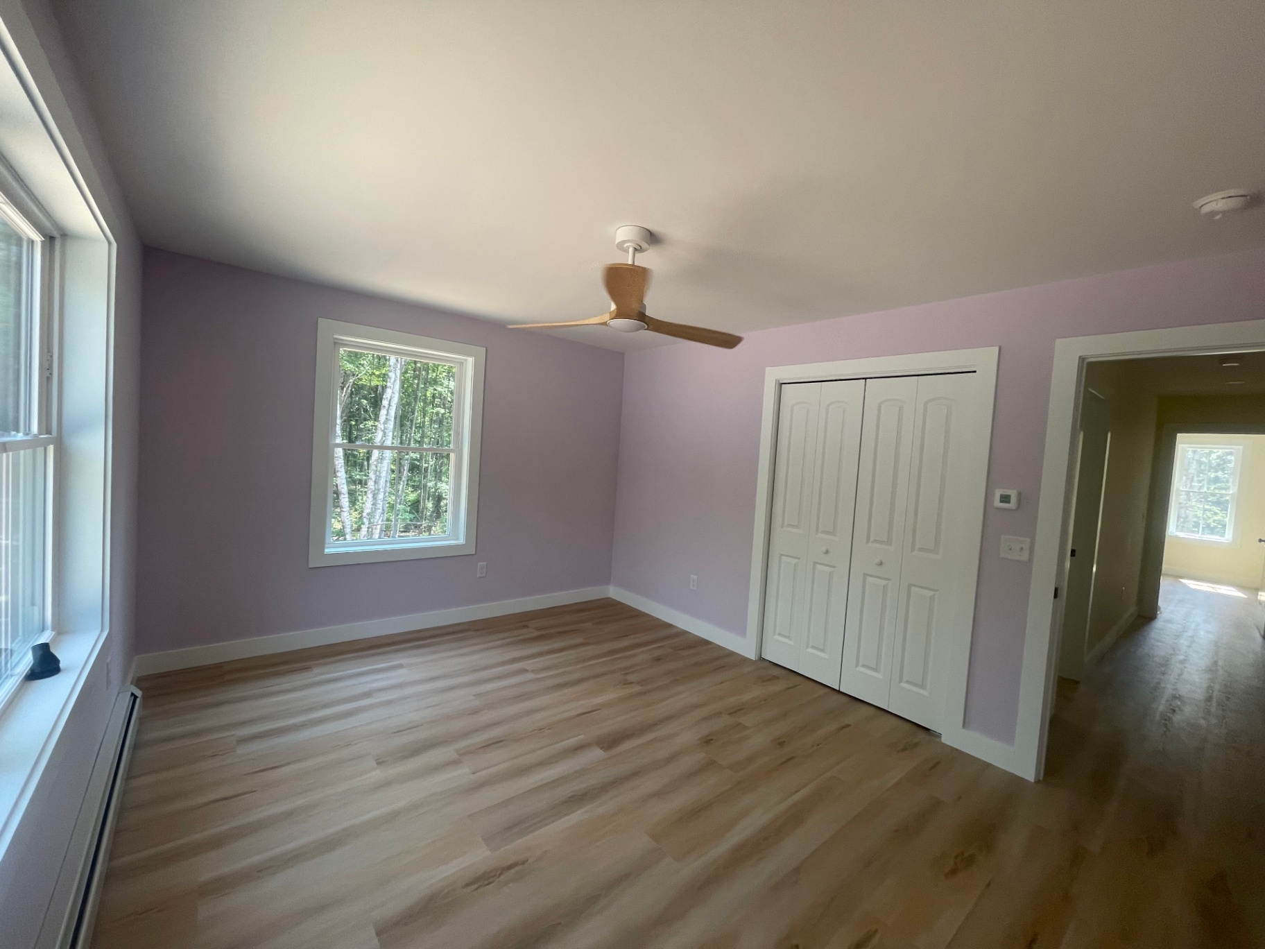 Bedroom with lavender accent walls, ceiling fan, and wide-plank LVP flooring