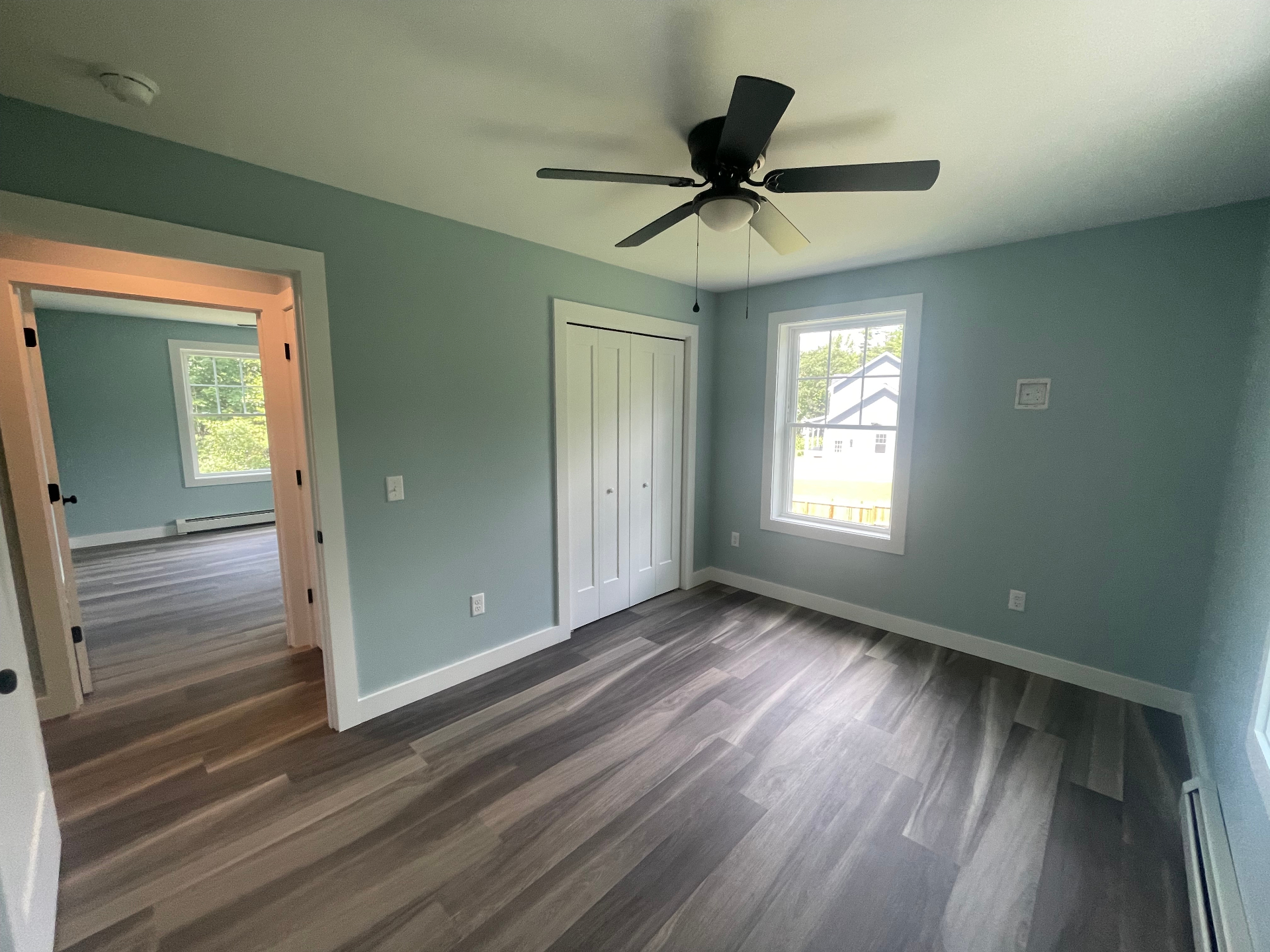 Bedroom with seafoam accent walls, ceiling fan, and wide-plank LVP flooring