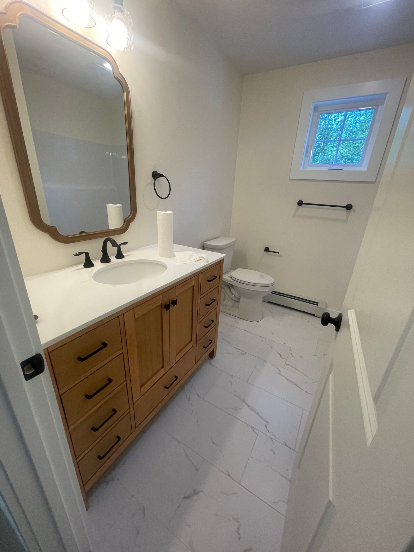 Bathroom vanity with Shaker cabinets, quartz countertop, and arched wood mirror