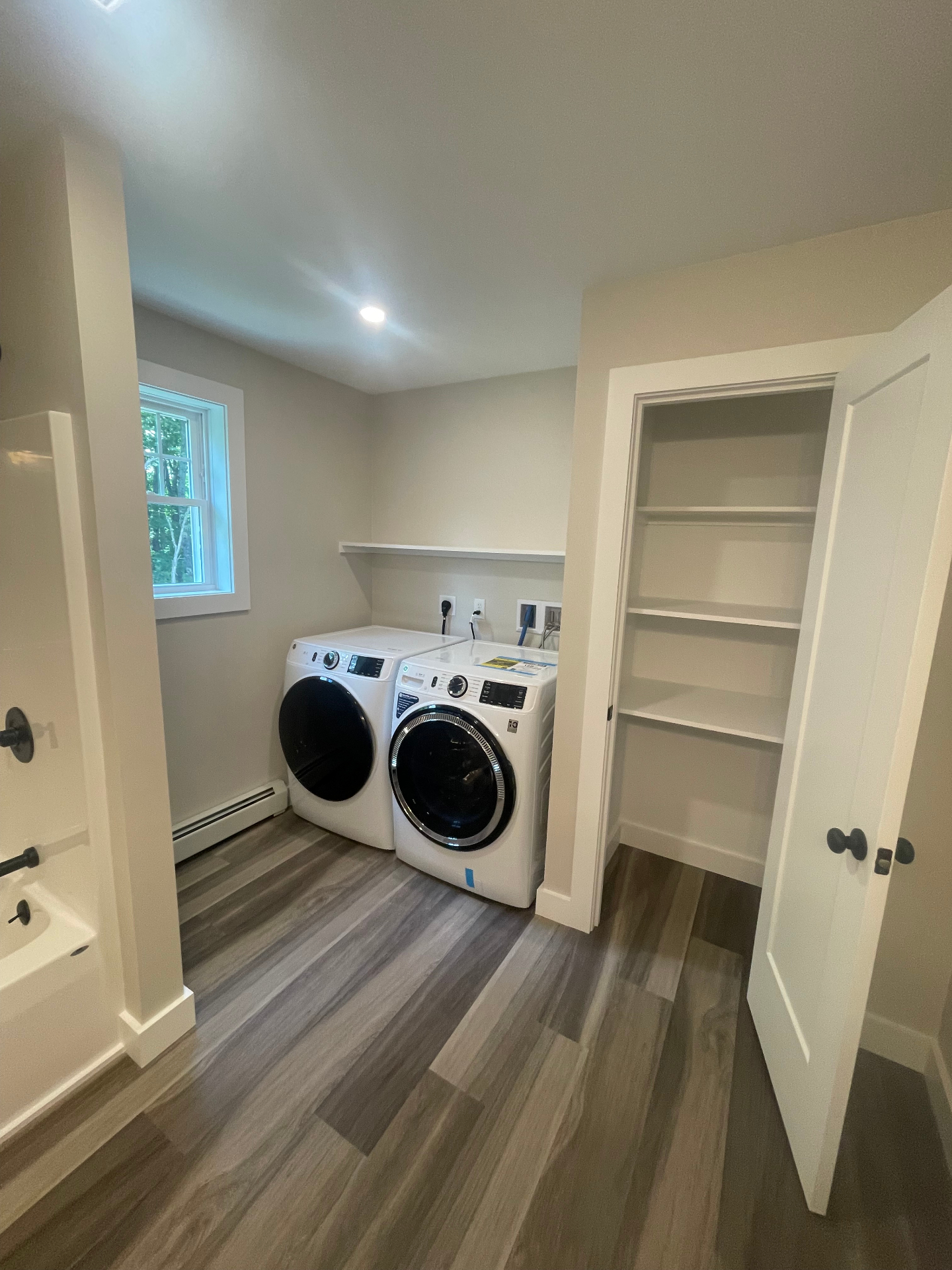 Second-floor laundry room with front-load washer and dryer and built-in linen closet
