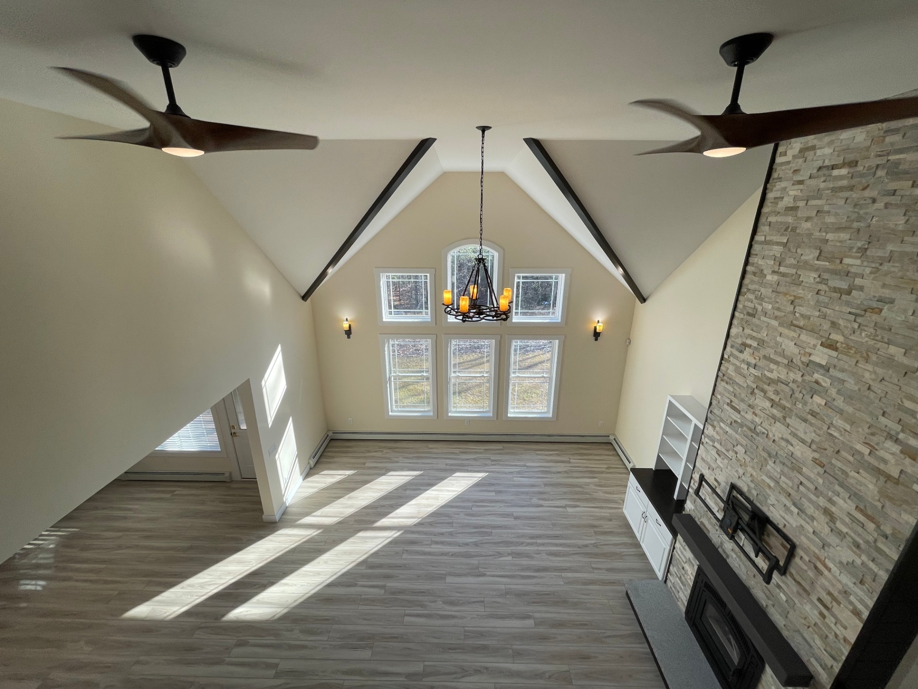 Cathedral great room with chandelier and stacked-stone fireplace