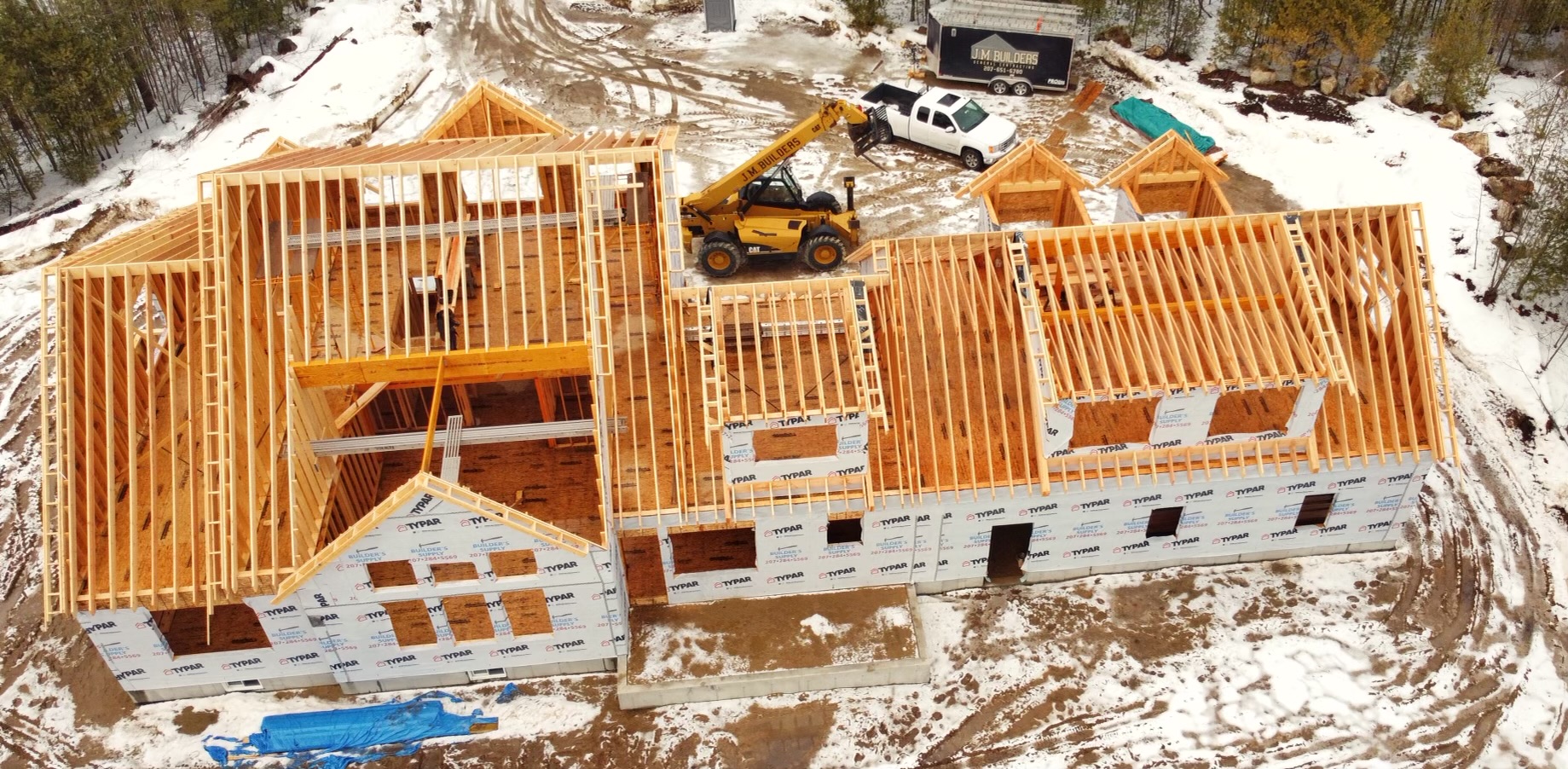 Roof framing in progress over snowy ground